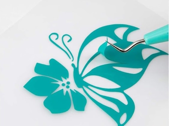 Close-up of a weed cutter pulling a piece of excess vinyl from a butterfly on a flower made of permanent adhesive vinyl in Tiffany blue.